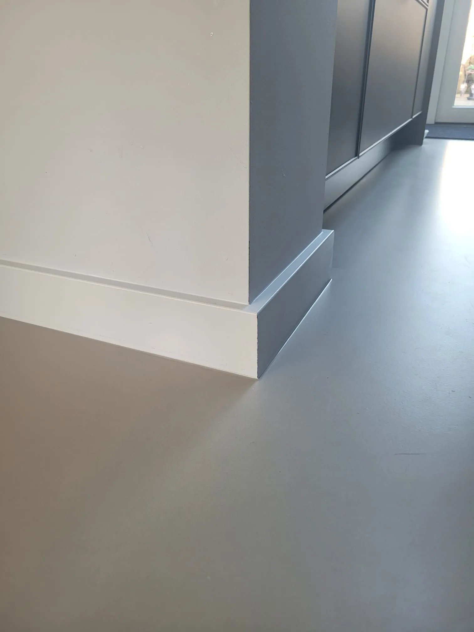 Hoekdetail van hoge plint met kleurcontrast op gietvloer