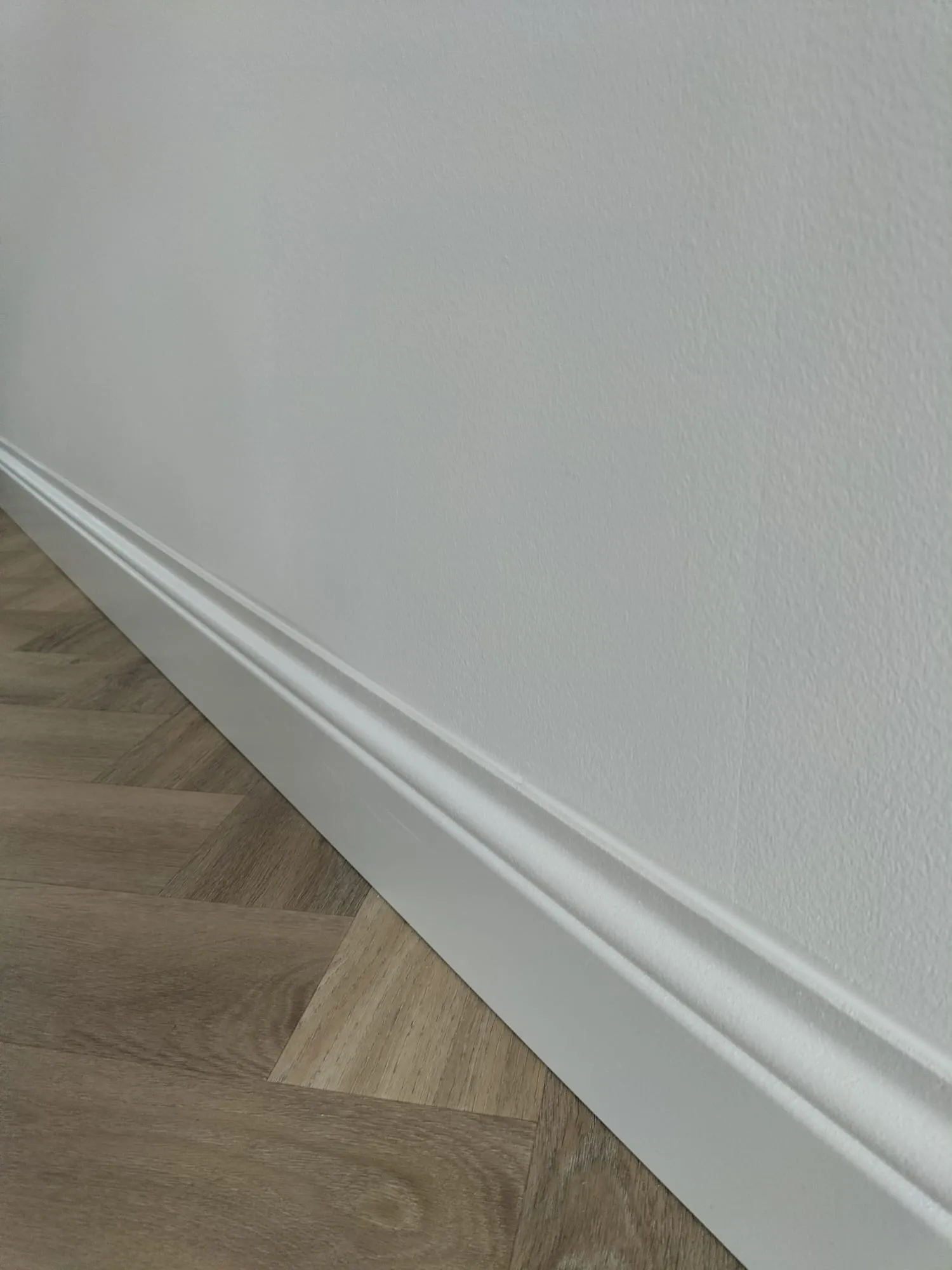 Hoge witte plint op visgraatvloer in luxe woonkamer