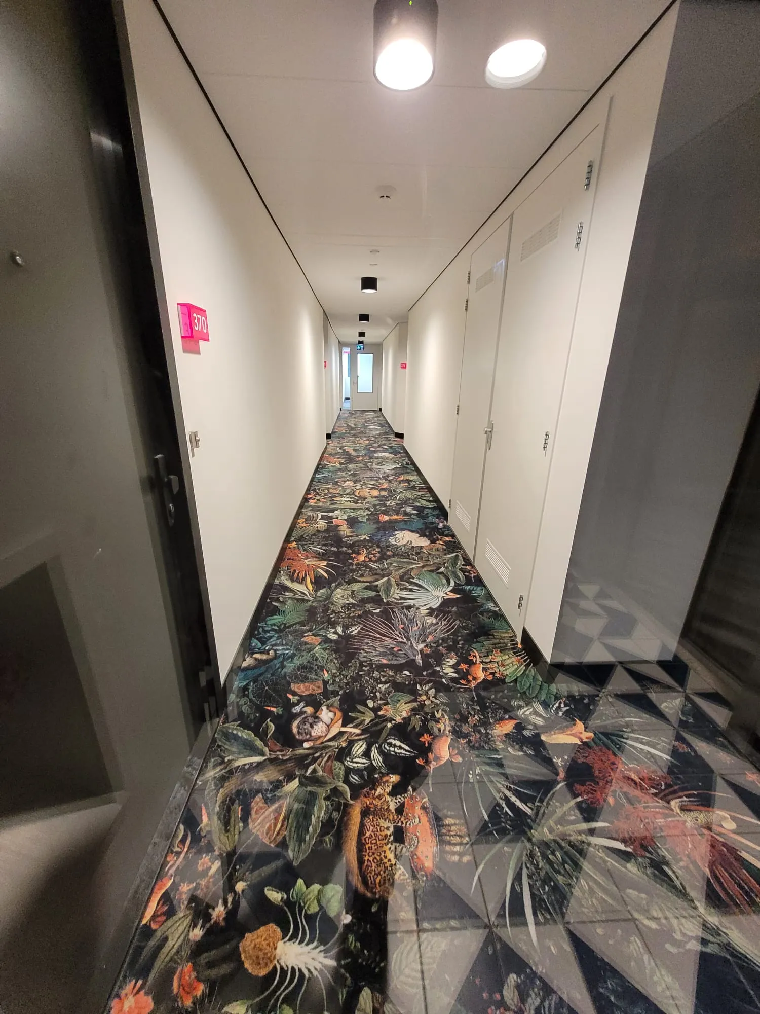 Hotelgang met wandpanelen, zwarte plinten en tapijt