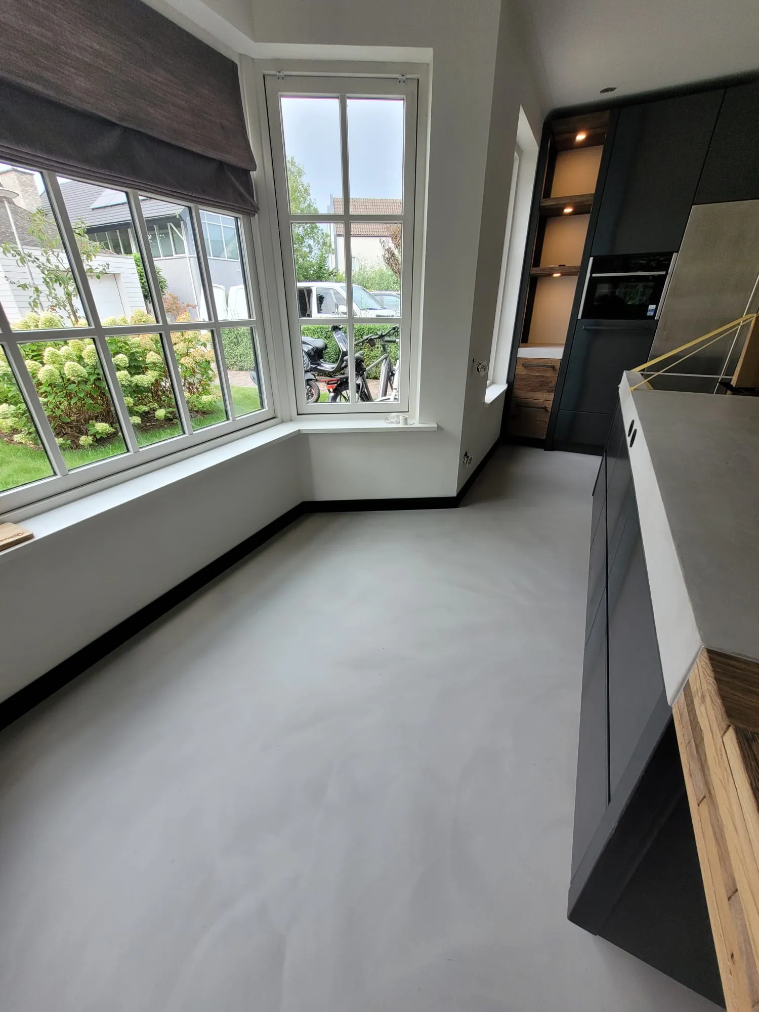Moderne keuken met beton ciré achterwand, gietvloer en zwarte plint